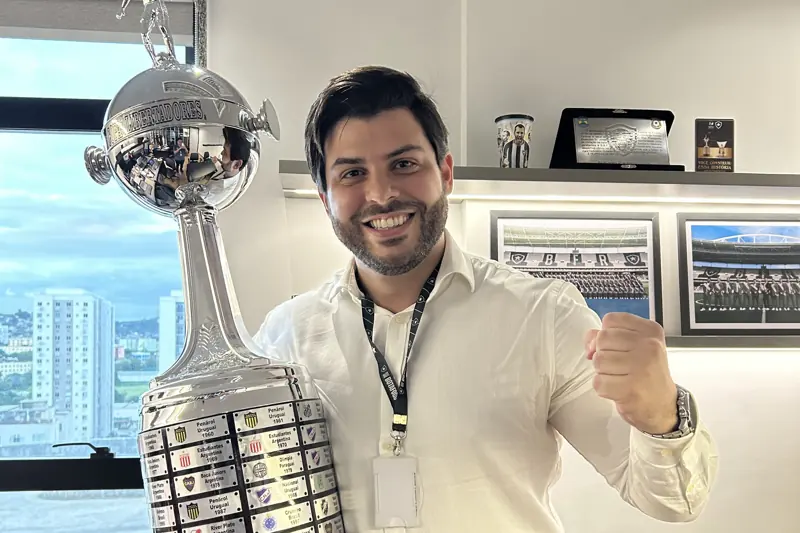Allan Turano ao lado da taça da Libertadores, em sala do Botafogo