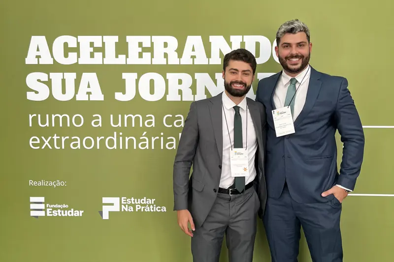 Carlos Macedo e Allan Turano diante do painel de uma conferência da Fundação Estudar