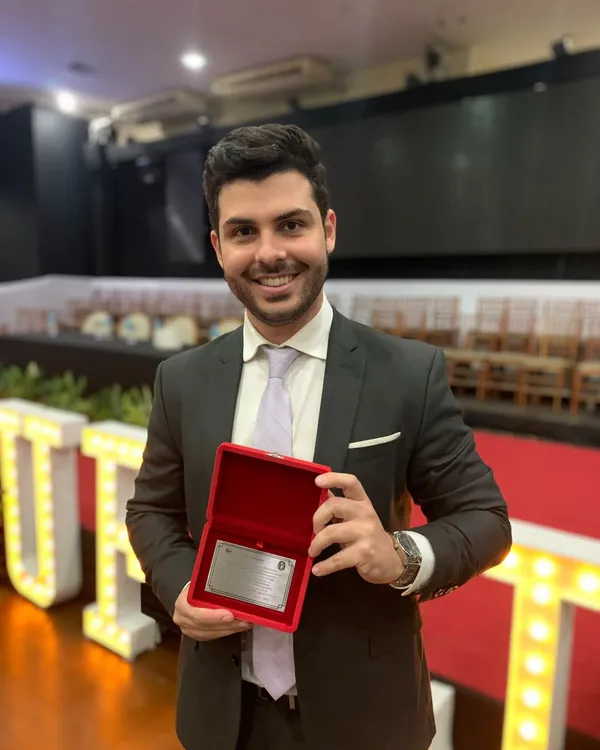 Allan Turano segura uma placa de homenagem