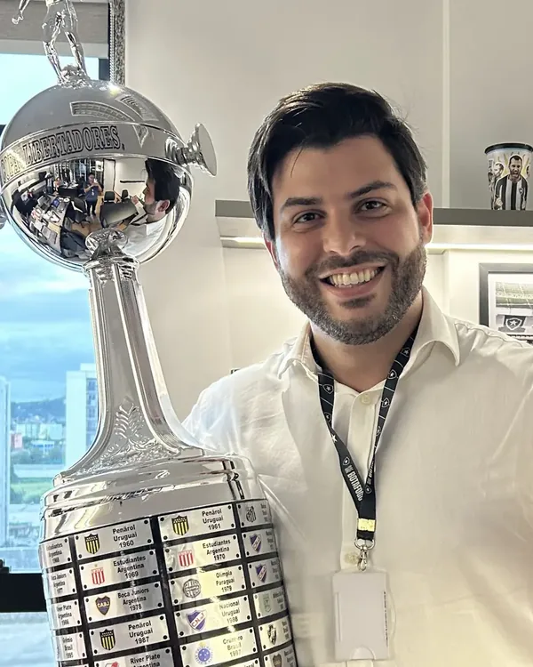 Allan Turano ao lado da taça da Libertadores, em sala do Botafogo