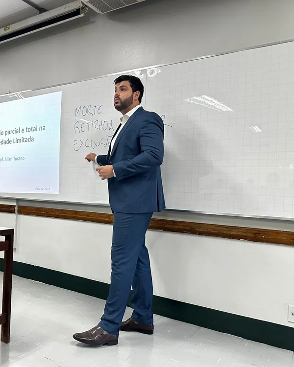 Allan Turano em sala de aula, ao lado de um slide sobre dissolução na sociedade limitada